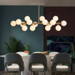 Mid-century modern linear brass chandelier featuring 16 glass globes against a dark luxury interior wall.