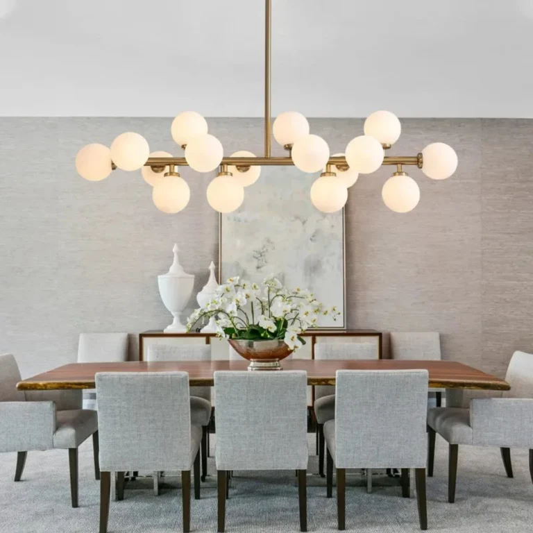 Modern 16-light linear dining chandelier with milk white glass globes installed over a large wooden dining table.