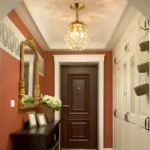 A luxury gold acorn pendant light installed in a classic entryway with warm terracotta walls.