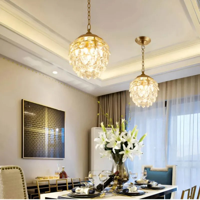 Two luxury pine cone modern gold crystal chandelier hanging above an elegant dining table with white lilies.