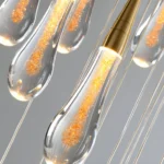 Close-up of hand-blown teardrop glass pendant showing the unique bubble texture and light refraction.