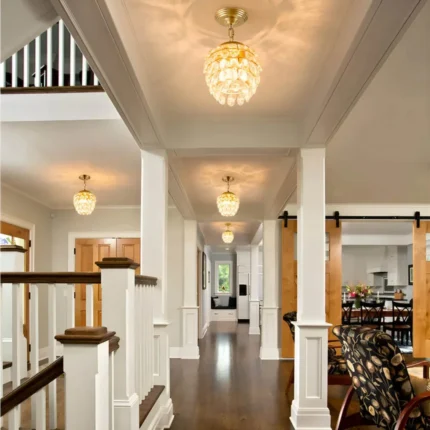 Multiple mini gold crystal chandeliers used as luxury foyer lighting along a grand hallway.