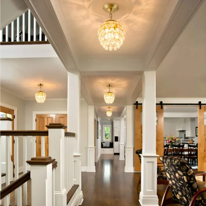 Multiple mini gold crystal chandeliers used as luxury foyer lighting along a grand hallway.