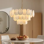 Modern alabaster chandelier with gold frame over round marble dining table in luxury home