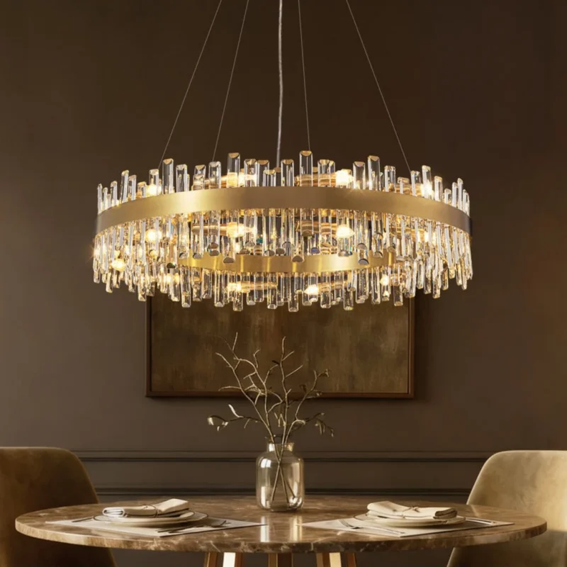 Modern antique brass crystal chandelier installed over a round marble dining table.