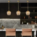 Three modern acorn-shaped gold pendant lights installed over a high-end kitchen island.
