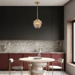 A small gold crystal chandelier in pine cone shape providing warm light in a modern kitchen setting.