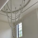 Beaded chandelier with necklace style crystal drapery installed in a luxury high ceiling interior