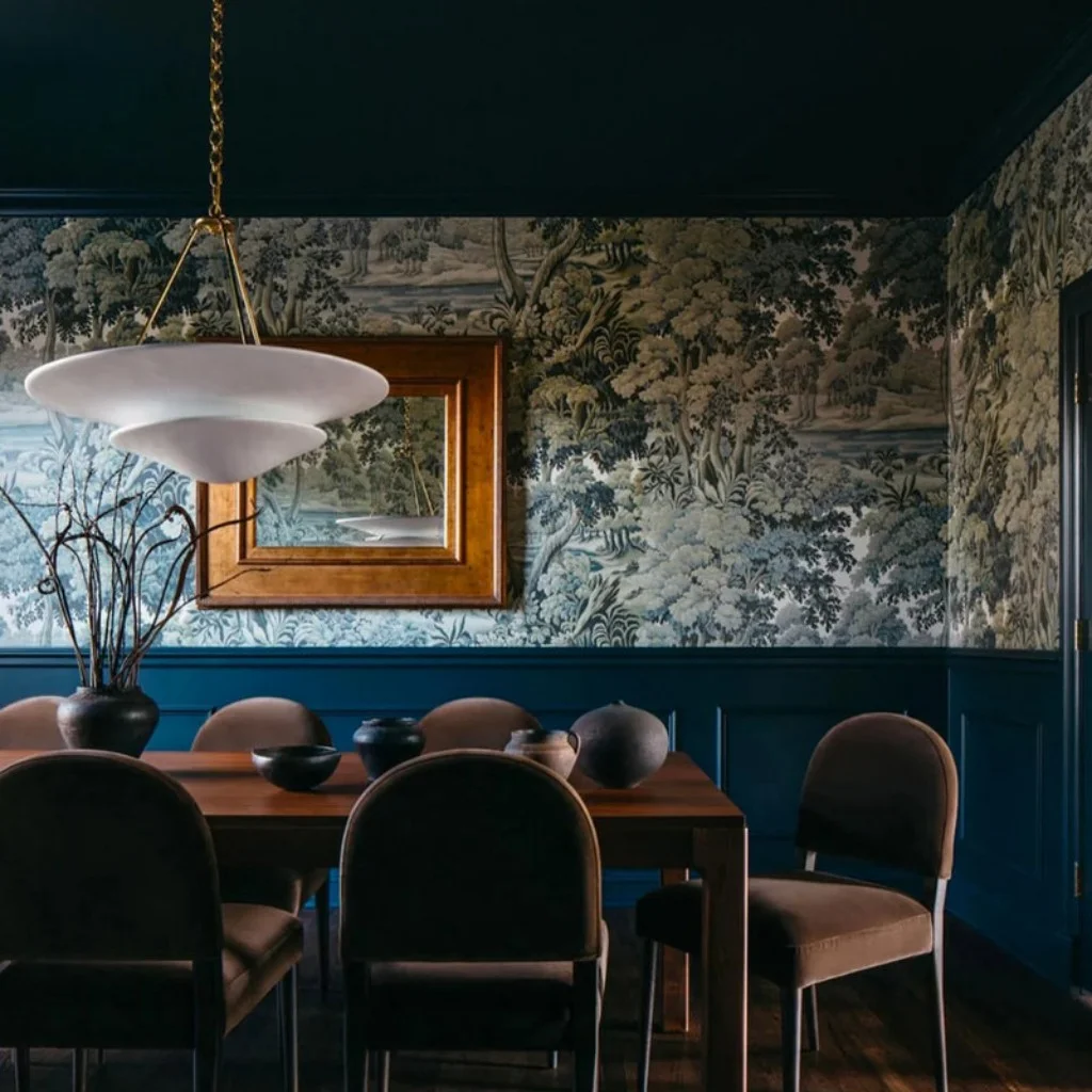 vintage style alabaster pendant light hanging above a solid wood dining table in a luxury dining room with green forest wallpaper