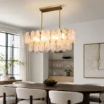 Modern linear chandelier with hand-blown glass and gold frame over a dining table