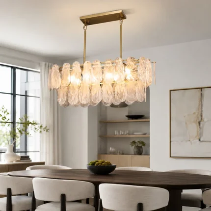 Modern linear chandelier with hand-blown glass and gold frame over a dining table