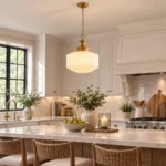Milk glass pendant light with gold frame hanging above a kitchen island