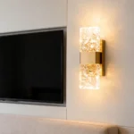 Gold crystal wall sconce installed beside a television in a modern living room