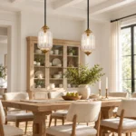 Two clear glass pendant lights with vintage bronze details hanging above a wooden dining table.