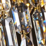 Macro detail of clear faceted rectangular crystal prisms and teardrop pendants connected by gold metal hooks