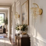 Pair of Style C gold crystal wall sconces with cascading crystal strands along a bright hallway wall
