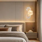 Single three-flower glass wall sconce mounted above a bedside table beside an upholstered bed