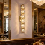 Gold crystal wall sconce with vertical faceted crystal sections beside a mirrored dining area