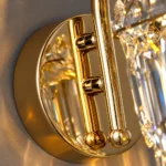 Close-up of reflective gold circular wall mounting plate and metal support rods on a crystal wall sconce
