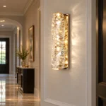 Gold crystal wall sconce illuminating an elegant residential hallway and entryway