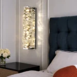 Chrome rectangular K9 crystal wall sconce installed beside a bed with warm lighting