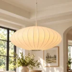Japanese lantern pendant light with glowing white imitation silk shade hanging above a dining table