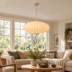 Warm white lantern pendant light hanging above a round wooden coffee table in a neutral living room