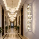 Long crystal wall sconce mounted in an elegant corridor with ceiling chandeliers and marble floors