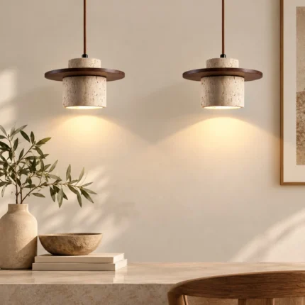 Two natural stone pendant lights with dark wood accents hanging above a stone console in a warm neutral interior.