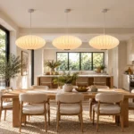 Three white lantern pendant lights illuminating a kitchen island in an open-plan kitchen and dining space